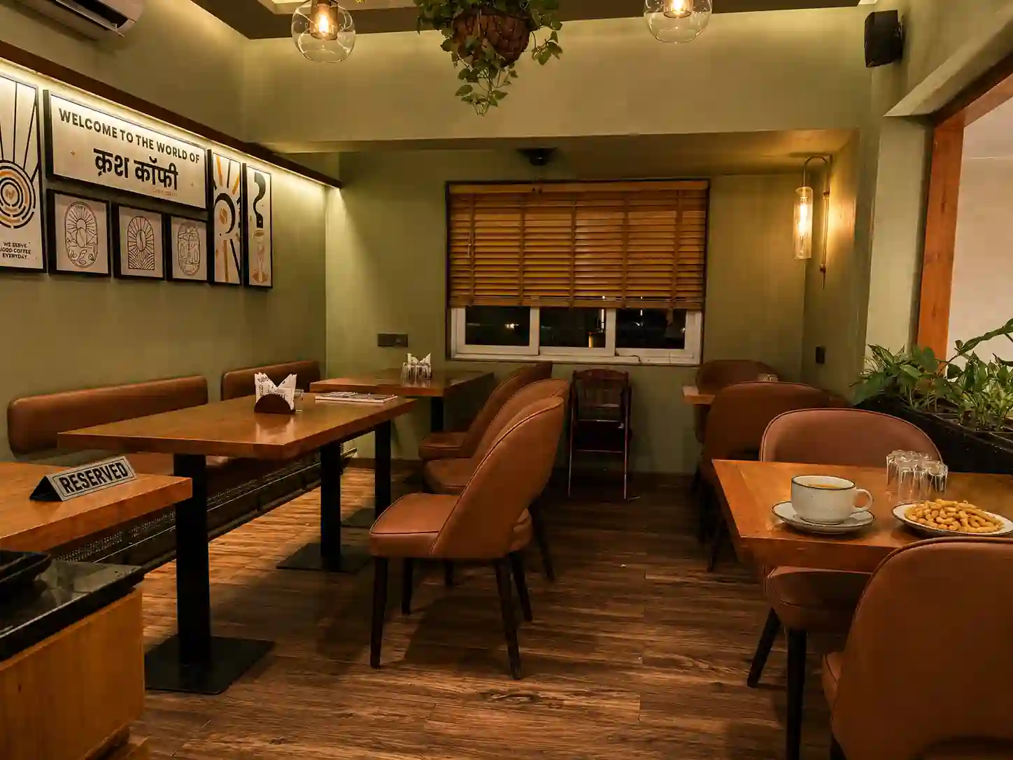 Earthy sage green walls and cozy wooden tables inside Crush Coffee CG Road Ahmedabad